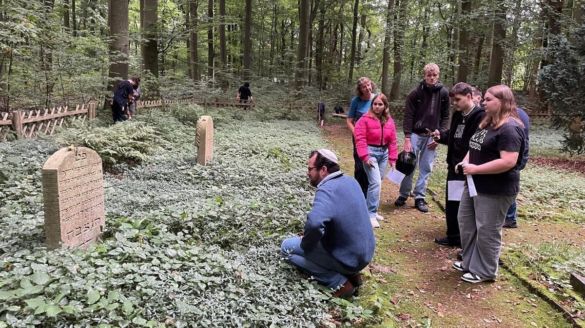 Rabbi Jona Simon mit Schülerinnen und Schülern der BBS am ältesten Grabstein auf dem jüdischen Friedhof Brockeswalde. Das Grab stammt aus dem Jahr 1802. Foto: Kramp