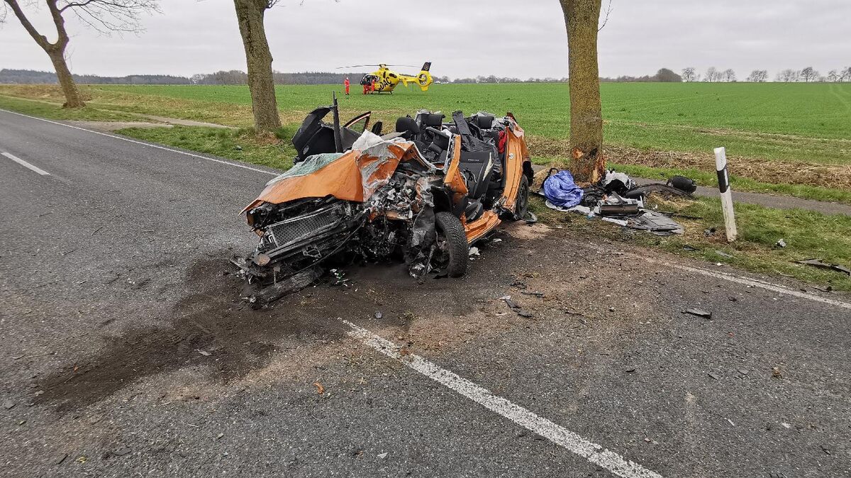 Das Fahrzeugwrack nach dem Unfall: Im Hintergrund ist der Rettungshubschrauber zu sehen, der auf einem Feld landete. Foto: Polizei