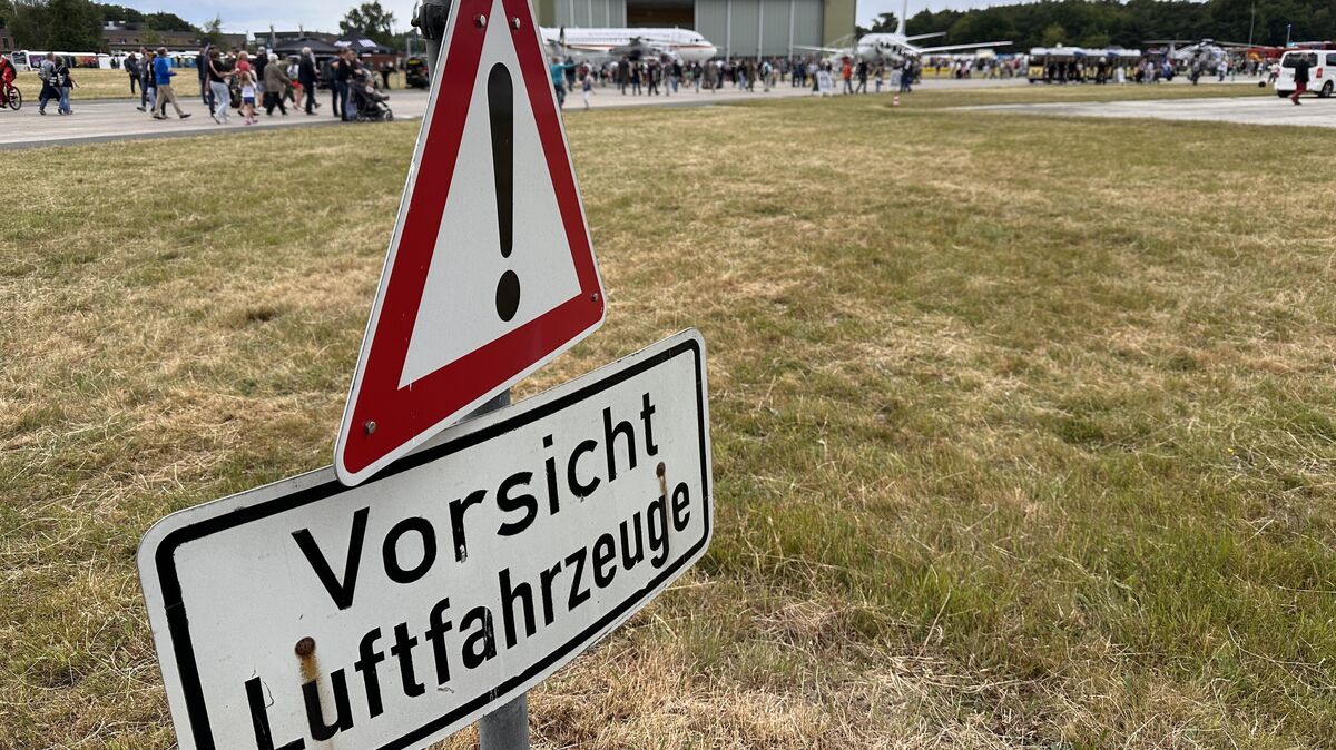 „Achtung, Luftfahrzeuge!" – Ein warnendes Schild erinnert die Besucher des Tags der Bundeswehr in Nordholz daran, dass sie sich auf einem aktiven Flugplatz befinden, während im Hintergrund die Faszination für die ausgestellten Maschinen spürbar ist. Foto: Reese-Winne