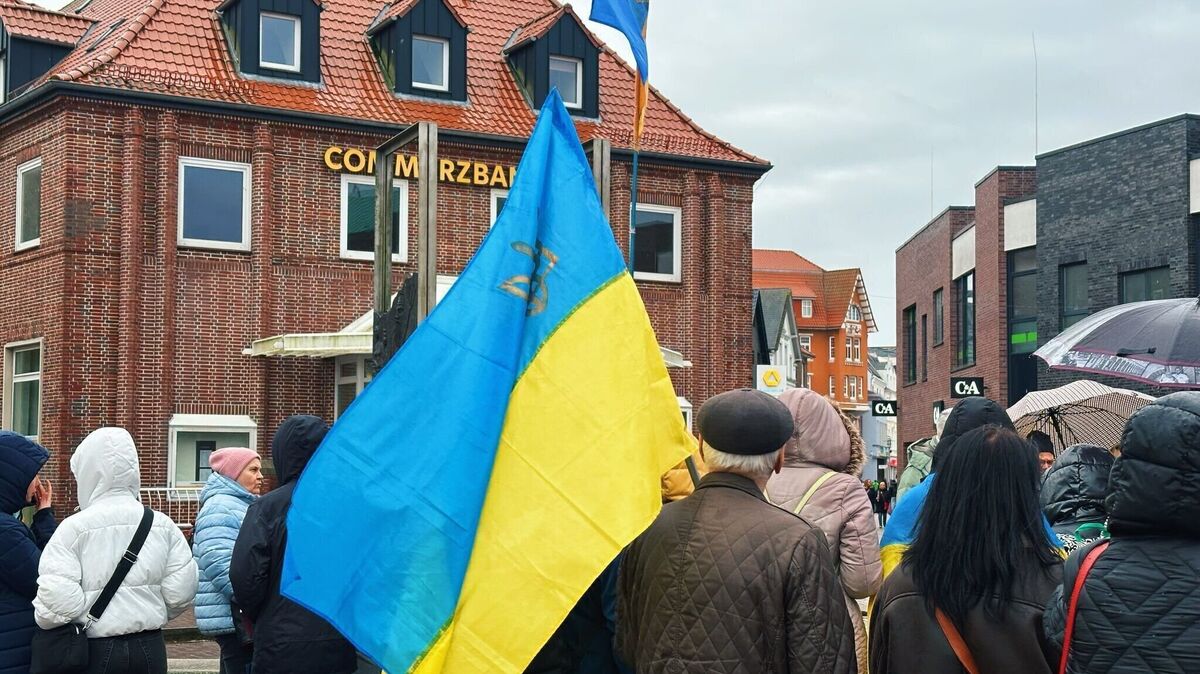Blaue und gelbe Fahnen zieren den Kaemmererplatz, während Menschen der Opfer des Krieges gedenken. Foto: Francke