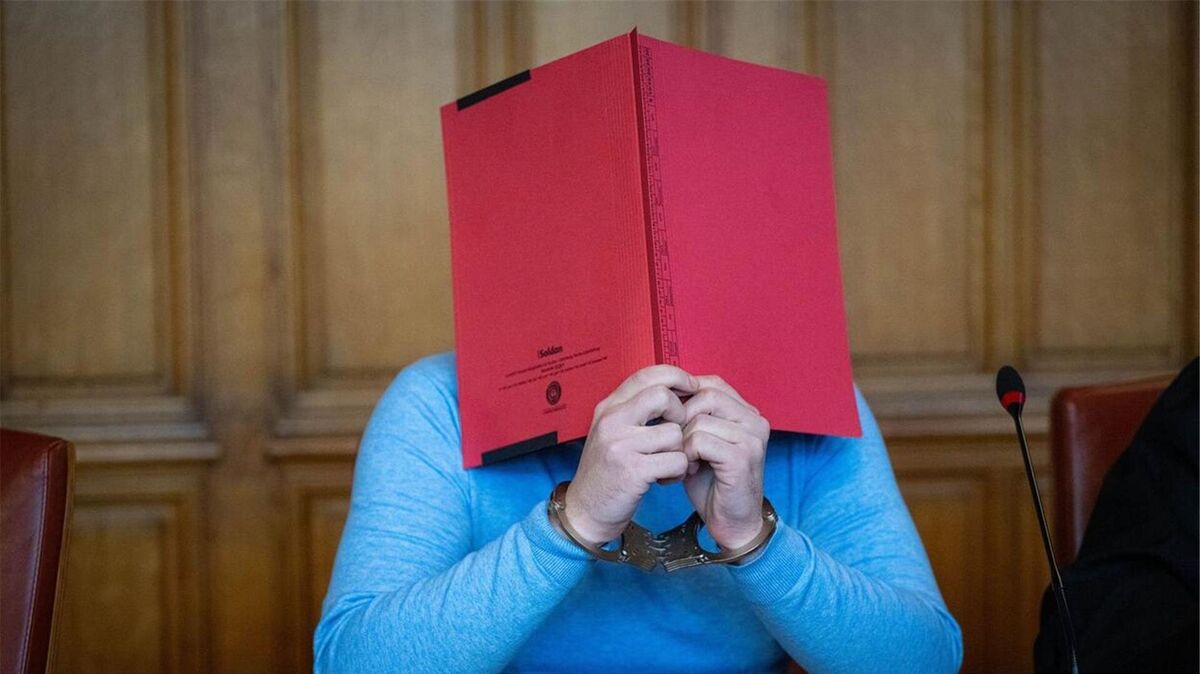 Hinter einer roten Mappe verborgen: Vor dem Landgericht Bremen muss sich ein 35-jähriger Ex-Tanztrainer wegen schweren sexuellen Missbrauchs von Kindern und Jugendlichen verantworten. Foto: Sina Schuldt