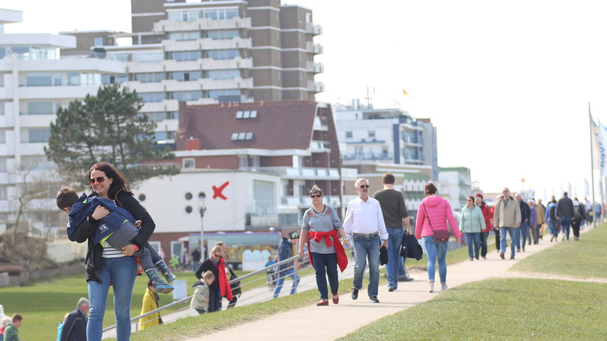Spaziergänger genießen die frische Luft an der Küste von Cuxhaven, während die Debatte um die Tourismusabgaben anhält. Foto: Potschka