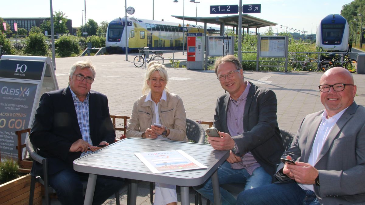 Oberbürgermeister Ulrich Getsch (l.) schaltete am Freitagmorgen zwei WLAN-Hotspots im Cuxhavener Bürgerbahnhof frei. Hilke von der Reith, Axel Schneider und Jürgen von Ahnen (v.l.n.r.) machten auf dem Vorplatz zu den Gleisen die Probe aufs Exempel. Foto: Potschka