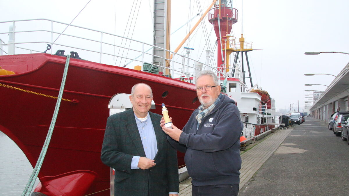 Wolfgang Petermann (links), Vorsitzender der Bürgerinitiative Cuxhaven, überreicht Bernd Petersen, Vorsitzender des Fördervereins Feuerschiff "Elbe 1", den „Goldenen Leuchtturm" vor dem Bug der „Roten Lady". Mit der Auszeichnung würdigt die Initiative das jahrzehntelange ehrenamtliche Engagement für das historische Feuerschiff, das zurzeit im Winterquartier im Neuen Fischereihafen liegt. Foto: Potschka