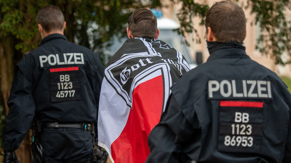 Ein Demonstrant mit einer schwarzrotweißen Flagge mit einem Eisernen Kreuz darauf wird von zwei Polizisten abgeführt. Ein sogenannter Reichsbürger aus Cadenberge ist nun festgenommen worden. Symbolfoto: Christophe Gateau/dpa