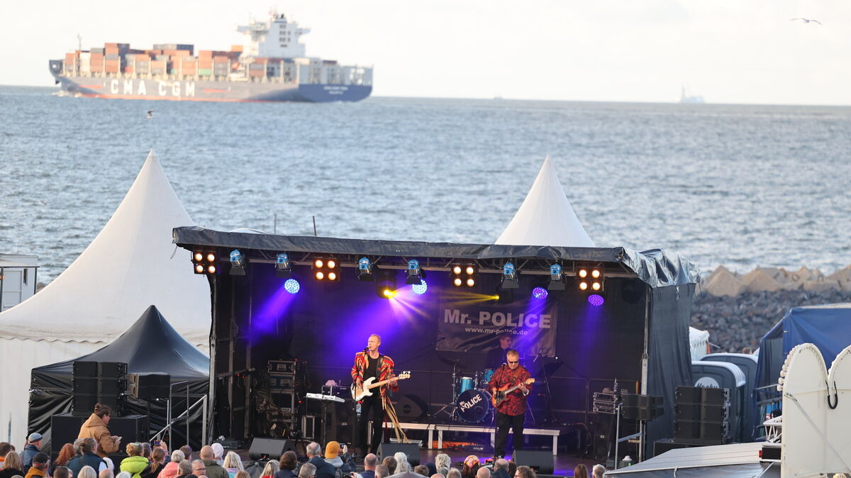 Besucher genießen den Sound von Mr. Police vor der malerischen Kulisse der Elbmündung in Cuxhaven. Foto: Jens Potschka