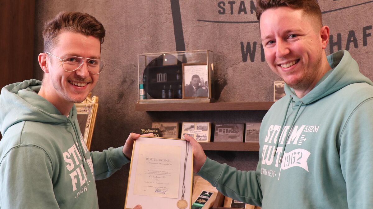 Timo (rechts) und Dennis Klamt - hier mit einer 60 Jahre alten Flut-Medaille - haben zusammen mit dem Cuxhavener Unternehmer Jan Fitter eine ganze Produktpalette rund um die Sturmflut von 1962 entwickelt. Foto: Mangels