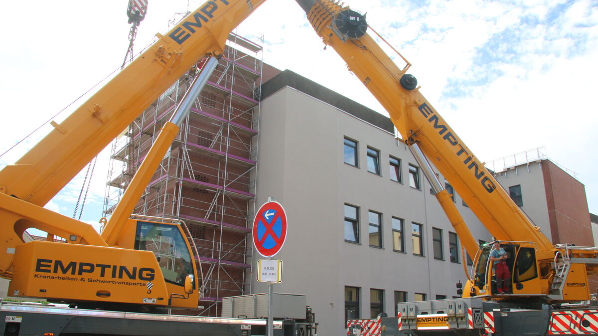Die beiden tonnenschweren Empting-Kräne stehen vis-à-vis auf der Rückseite des ehemaligen Kaufhauses Woolworth in der Cuxhavener City. Kranführer und Arbeiter hieven derzeit Stahlträger und in Kürze Wandelemente und anderes sperriges Baumaterial auf das ehemalige Parkdeck des Geschäftshauses. Foto: Potschka