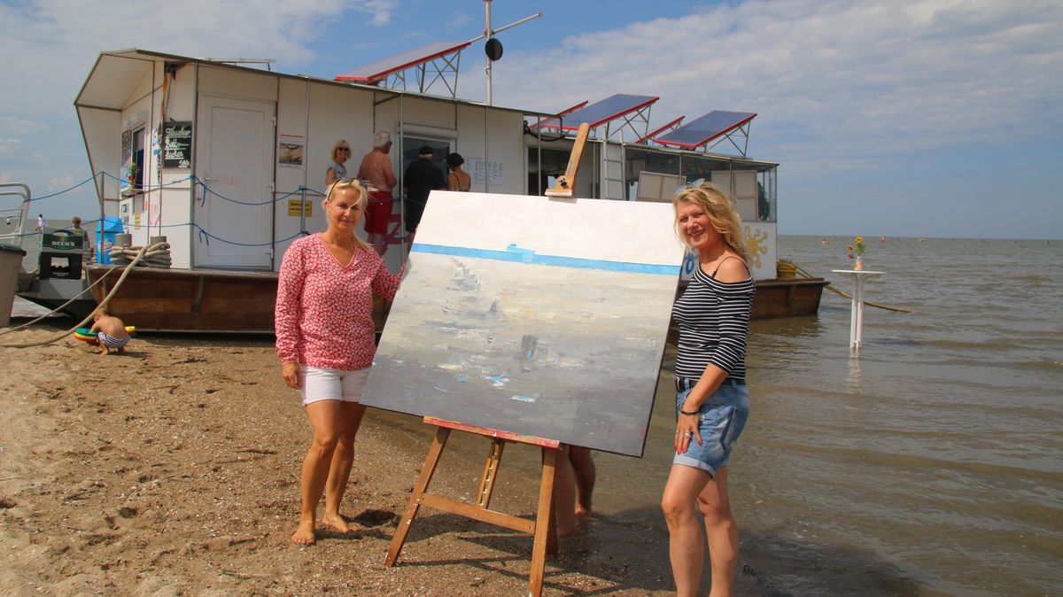 Zwei Freundinnen, eine Idee: die ehemalige Cuxhavenerin Claudia Schlenger (r.) stellt noch bis zum 1. September eine kleine Auswahl ihrer maritimen Bilder im Ponton Café von Claudia Sandt-Mahler in Cuxhaven-Duhnen aus. Die obige Arbeit beschäftigt sich mit dem Thema Wattverschlickung. Foto: Potschka