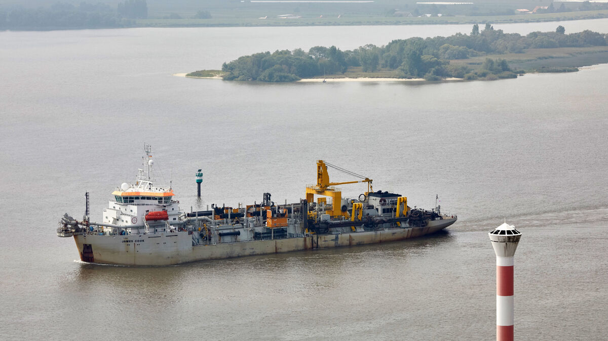 Das Baggerschiff „James Cook“ fährt auf der Elbe zwischen dem Leuchtturm Blankenese und einer Insel des Naturschutzgebiets Neßsand flussaufwärts. Foto: Wendt / dpa