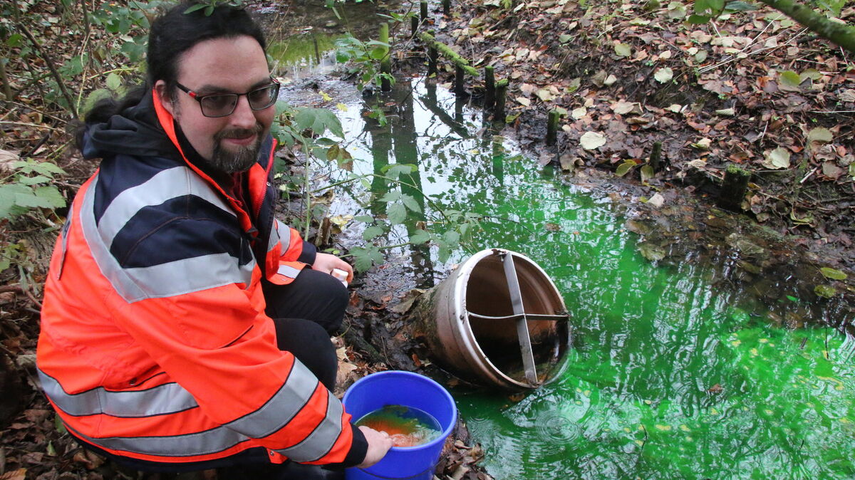Albrecht Roloff von der städtischen Wasserbehörde kippt einen Eimer mit grün eingefärbtem Wasser in den Schlossgraben. Das ist der Auftakt zu einem ausgeklügelten Versuch, den tatsächlichen Wasserweg nachzuvollziehen. Foto: Potschka
