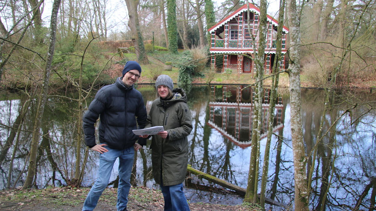Anja Stute und Dr. Christian Wolf, Fachbereichsleiterin der unteren Naturschutzbehörde und Naturschutzexperte der Stadt Cuxhaven, erläutern beim Ortstermin im Schlossgarten die Planzeichnung zur bevorstehenden Gewässersanierung. Im Hintergrund spiegelt sich das Schweizer Haus im trüben Wasser des Schlossgrabens, ein Gebäude, dessen Schutz vor künftigen Starkregenereignissen zu den zentralen Planungsaufgaben zählt. Foto: Potschka