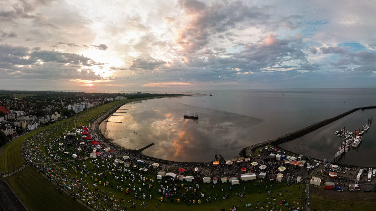 Sommerabendstimmung in der Grimmershörnbucht: Tausende versammeln sich am Ufer von Cuxhaven, um beim Musikwochenende den Klängen von Stefanie Heinzmann und anderen Künstlern zu lauschen, während die Sonne malerisch über dem Meer untergeht. Foto: Nordseeheilbad Cuxhaven GmbH