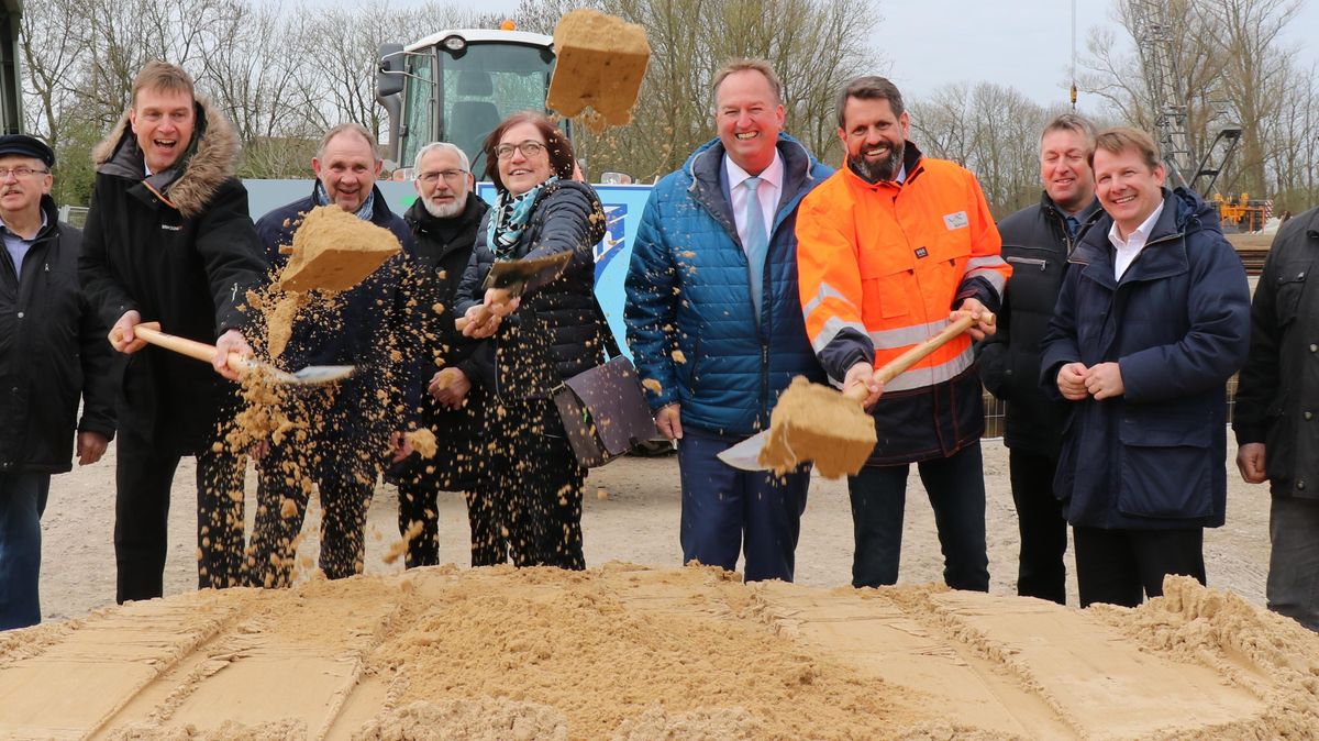 Zwei Männer und eine Frau greifen zur Schaufel: Umweltminister Olaf Lies (4.v.r.), Landrat Kai-Uwe Bielefeld (3.v.l.) und NLWKN-Direktorin Anne Rickmeyer nehmen den symbolischen ersten Spatenstich an der Otterndorfer Schleuse vor. Foto: Mangels