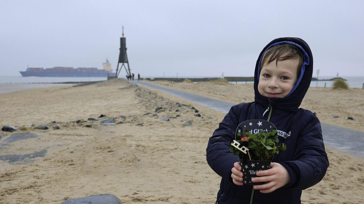 Der siebenjährige Finn Tovenrath lässt sich an der Kugelbake trotz des miesen Wetters nicht die Freude auf das neue Jahr nehmen - und hält den Glücksklee fest in seinen Händen. Foto: May