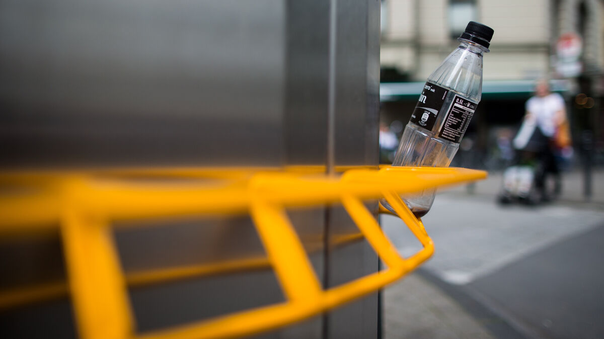 Eine Pfandflasche steckt in einem Pfandring an einem öffentlichen Mülleimer. Die Vorrichtung soll Flaschensammlern die Arbeit erleichtern - und verhindern, dass sie den in der Tonne befindlichen Abfall durchwühlen müssen. Foto: Koppe