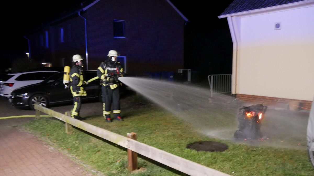 Unter Atemschutz führen zwei Feuerwehrleute einen Löschangriff aus einem wasserführenden Fahrzeug auf die noch brennende Mülltonne aus. Foto: Lange