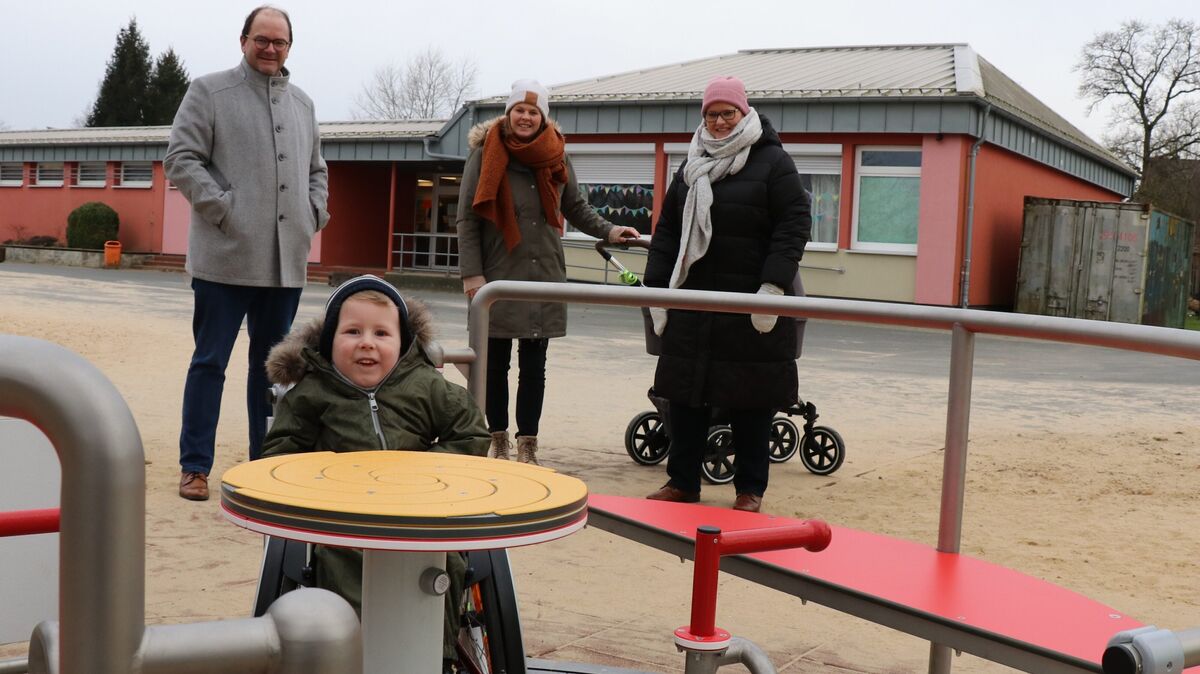 Dank des Inklusionskarussells kann nun auch Theo Spaß auf dem Spielplatz der Grundschule Wanna haben. Bürgermeisterin Nicole Friedhoff (rechts), Gemeindedirektor Sönke Westphal und Theos Mutter, Berit Bursky (Mitte), freuen sich ebenfalls über das neue Spielgerät. Foto: Mangels
