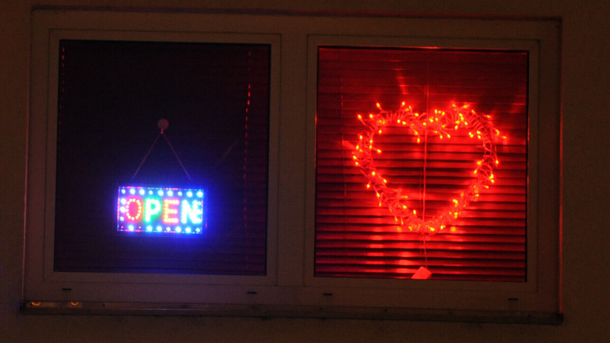 Fenster einer Wohnung mit leuchtendem "Open"-Schild und rotem Herz aus Lichtern: Ein Symbol für Wohnungsprostitution, die auch im Landkreis Cuxhaven an Bedeutung gewonnen hat. Foto: Patrick Seeger