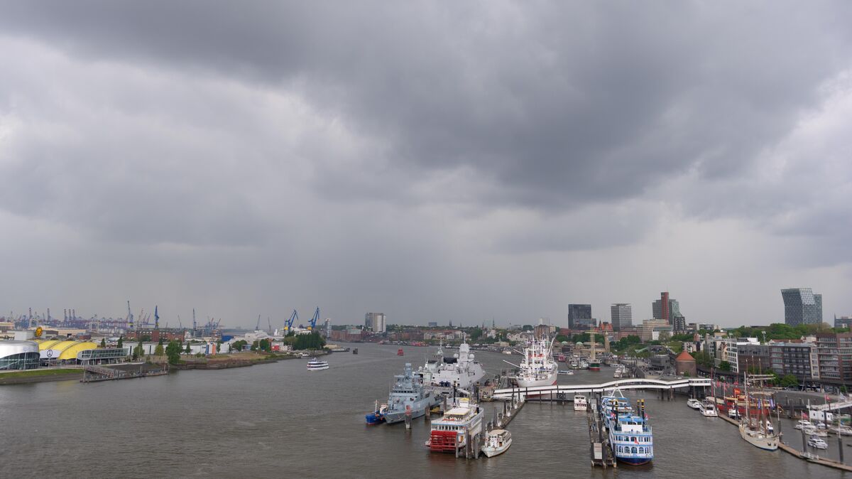 Graue Regenwolken über der Elbe und dem Hafen an der Überseebrücke. Die Elbe hat im Bereich Hamburg wieder mehr Sauerstoff im Wasser, dennoch ist die Situation für die Fische weiterhin angespannt. Foto: picture alliance/dpa | Jonas Walzberg