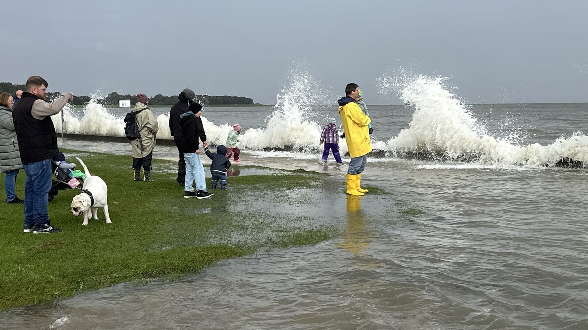 Schaulustige beobachten die Sturmflut in der Grimmershörnbucht – das Meer schäumt, der Deich hält stand.