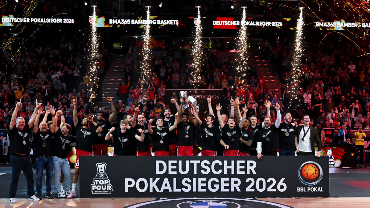 Die Spieler der Bamberg Baskets jubeln bei der Siegerehrung mit dem Pokal. Adrian Petkovic ist mittendrin (6.v.r.). Foto: dpa/Sven Hoppe