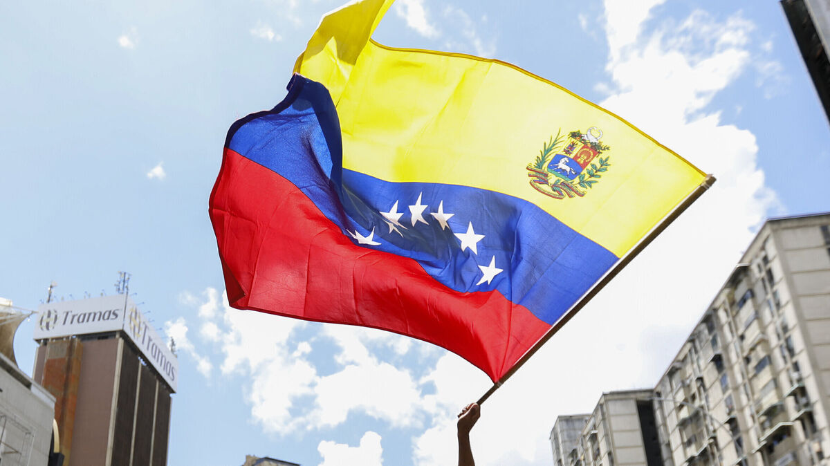 Eine venezolanische Flagge weht über den Straßen von Caracas, während Bürger für politische Veränderungen demonstrieren. Foto: dpa/Jeampier Arguinzones