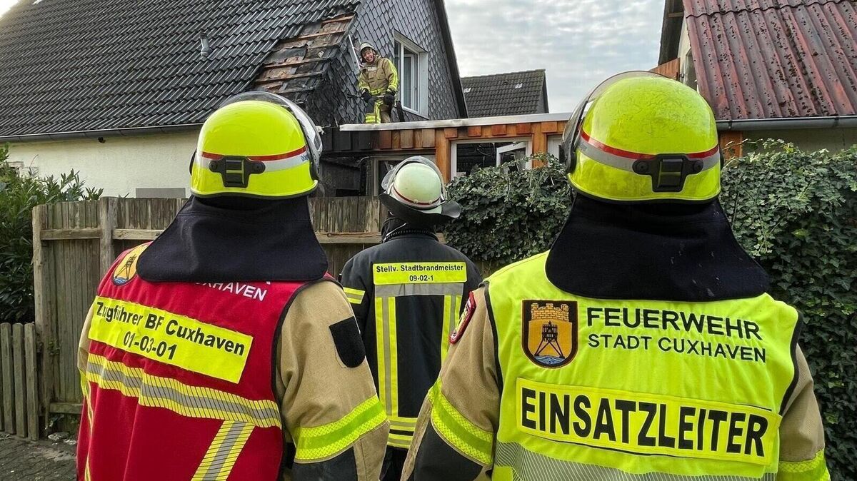 Einsatzkräfte untersuchen sorgfältig das Dach des Einfamilienhauses auf versteckte Glutnester. Dafür müssen auch Dachpfannen entfernt werden. Foto: Lütt