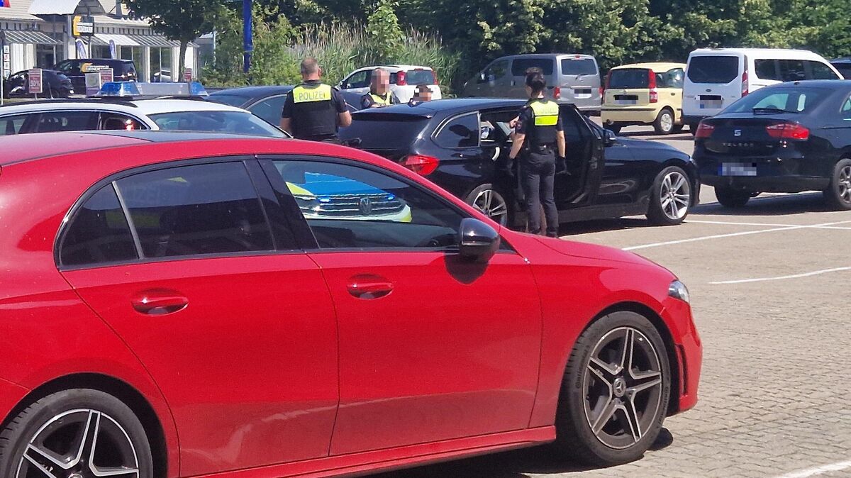 Polizeieinsatz auf dem Parkplatz: Zwei Spendensammler werden nach einem Platzverweis in Cuxhaven überprüft. Foto: Larschow