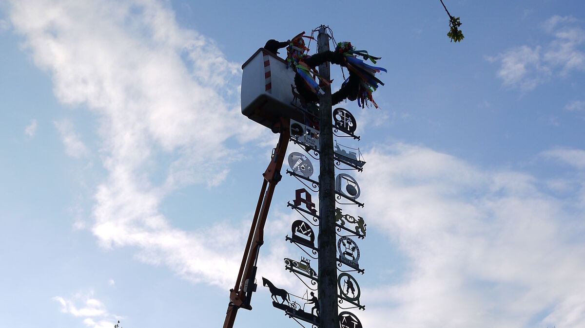 Der Maibaum in Altenwalde wird mit einem neuen Kranz geschmückt. Foto: Reese-Winne
