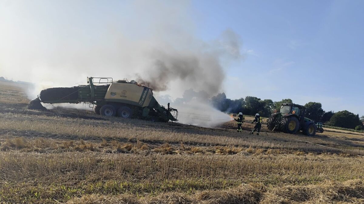 Mitten auf dem Feld steht die Strohpresse beim Eintreffen der ersten Kräfte in Vollbrand. Foto: Lange