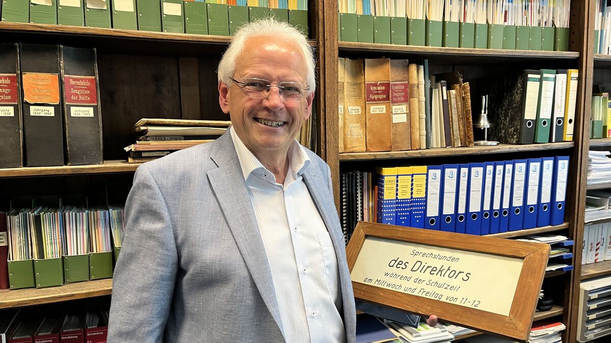 Wolfgang Deutschmann mag das historische Ambiente im Schulleitungszimmer des Amandus-Abendroth-Gymnasiums. Natürlich hat er auch das alte Hinweisschild auf die Sprechstunden des Direktors aufbewahrt. Foto: Reese-Winne