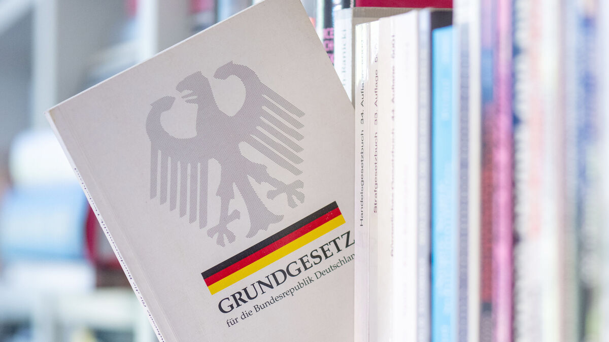 Ein Grundgesetz steckt in einem Bücherregal. Das Grundgesetz der Bundesrepublik feiert in diesem Jahr seinen 75. Geburtstag. Foto: Hendrik Schmidt/dpa