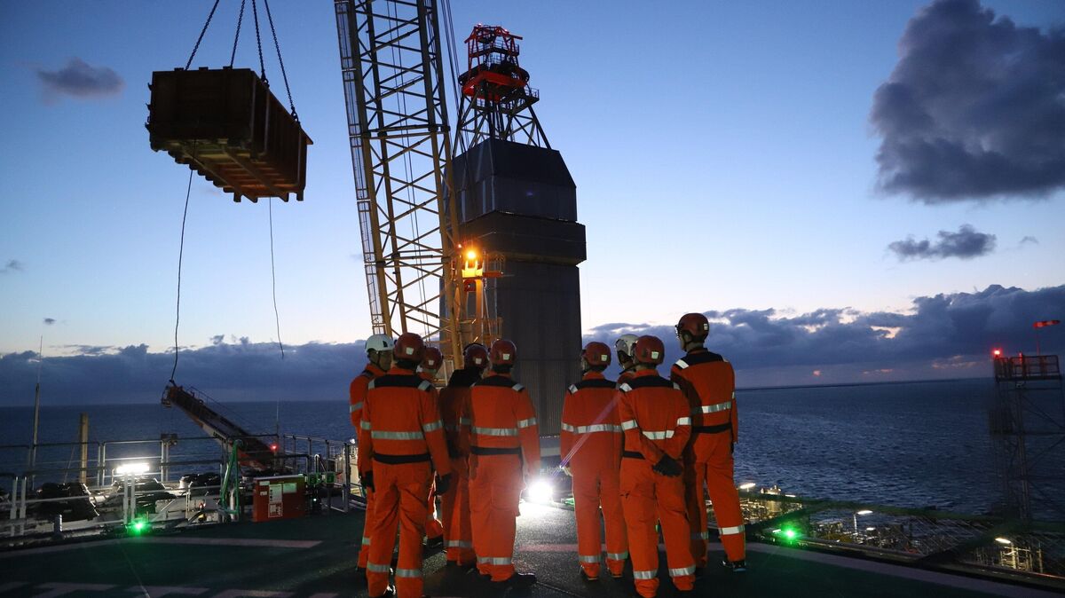 Besucher der Bohr- und Förderinsel in Schutzkleidung beobachten den Bohrturm und den Kran der Mittelplate vom Helikopterlandeplatz aus. Foto: Larschow