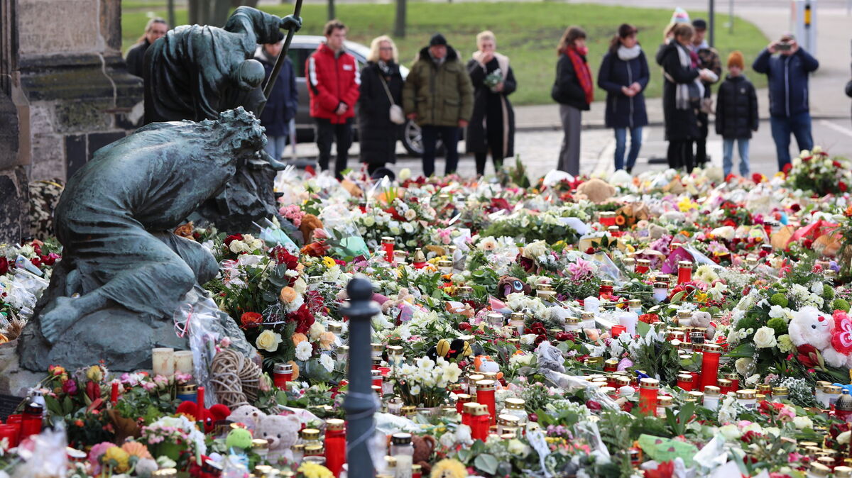 Trauernde stehen vor der Johanniskirche, dem zentralen Gedenkplatz nach dem Anschlag auf dem Magdeburger Weihnachtsmarkt, vor zahlreichen Kerzen, Blumen und Plüschtieren. Nachdem ein Auto in eine Menschenmenge auf dem Weihnachtsmarkt fuhr, hält die Trauer und Betroffenheit an. Foto: Matthias Bein/dpa