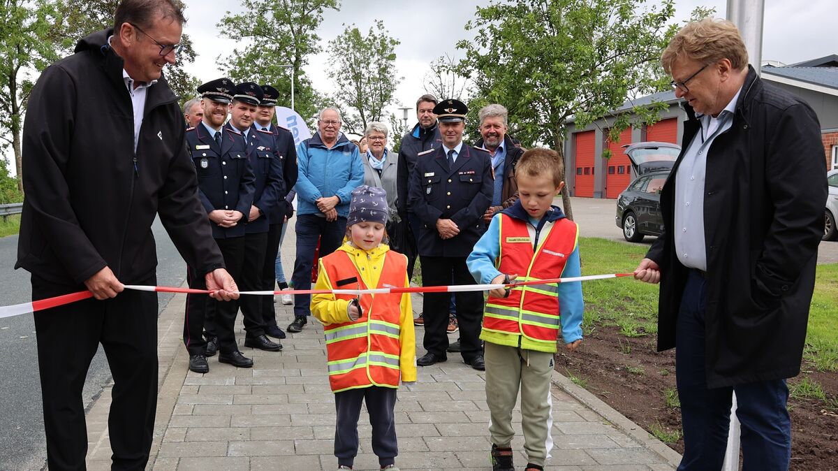 Die beiden Mitglieder der Kinderfeuerwehr, Clara Wichmann (6) und Tom Nagel (7), weihen den neuen Gehweg in Lüdingworth gemeinsam mit Ortsbürgermeister Thomas Brunken (links) und dem Baudezernent der Stadt Cuxhaven Andreas Eickmann ein. Foto: Stadt Cuxhaven