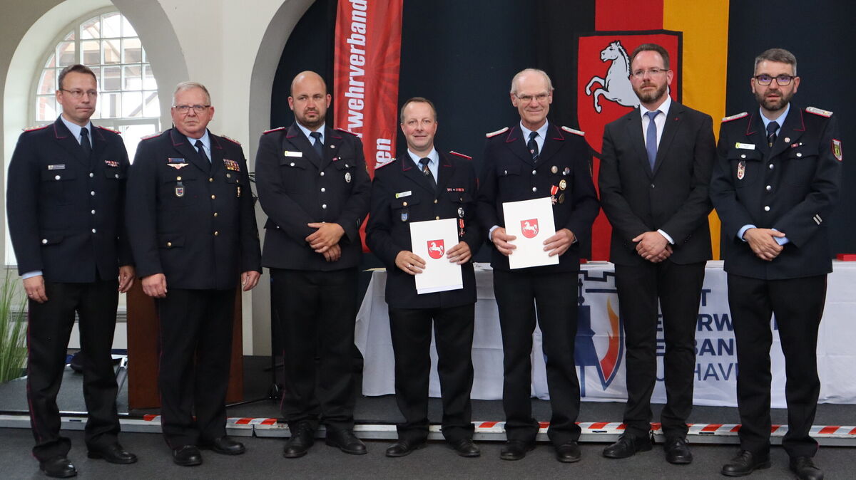 Dennis Joost und Sieghard Haude (Mitte v. l.) bekamen das silberne Feuerwehrabzeichen am Bande des Landes Niedersachsen verliehen. Umrahmt sind sie hier von Tim Fritsche, Gemeindebrandmeister Land Hadeln, Regierungsbrandmeister Thomas Friedhoff, dem stellvertretenden Stadtbrandmeister Christoph Zeuner, dem Ersten Stadtrat Markus Itjen und dem stellvertretenden Stadtbrandmeister Michael Zabel. Foto: Jesse König