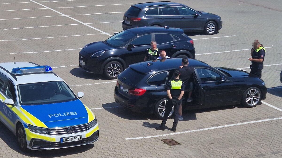 Zwei Polizistinnen und ein Polizist überprüfen auf einem Parkplatz die beiden Spendensammler. Foto: Larschow