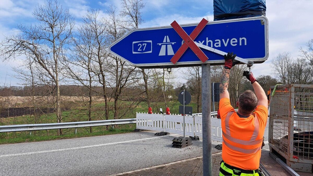 Ein Bauarbeiter entfernt das Gesperrt-Zeichen in Richtung Cuxhaven. Foto: Jan Iven