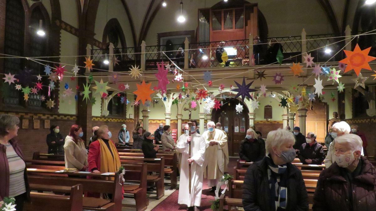 Mit Abstand und Masken: Einzug zum Festgottesdienst in den Kirchenraum, den Mitglieder des Fördervereins stundenlang mit Sternen aus der Aktion "Sterne im Advent" geschmückt hatten. Foto: Hönick