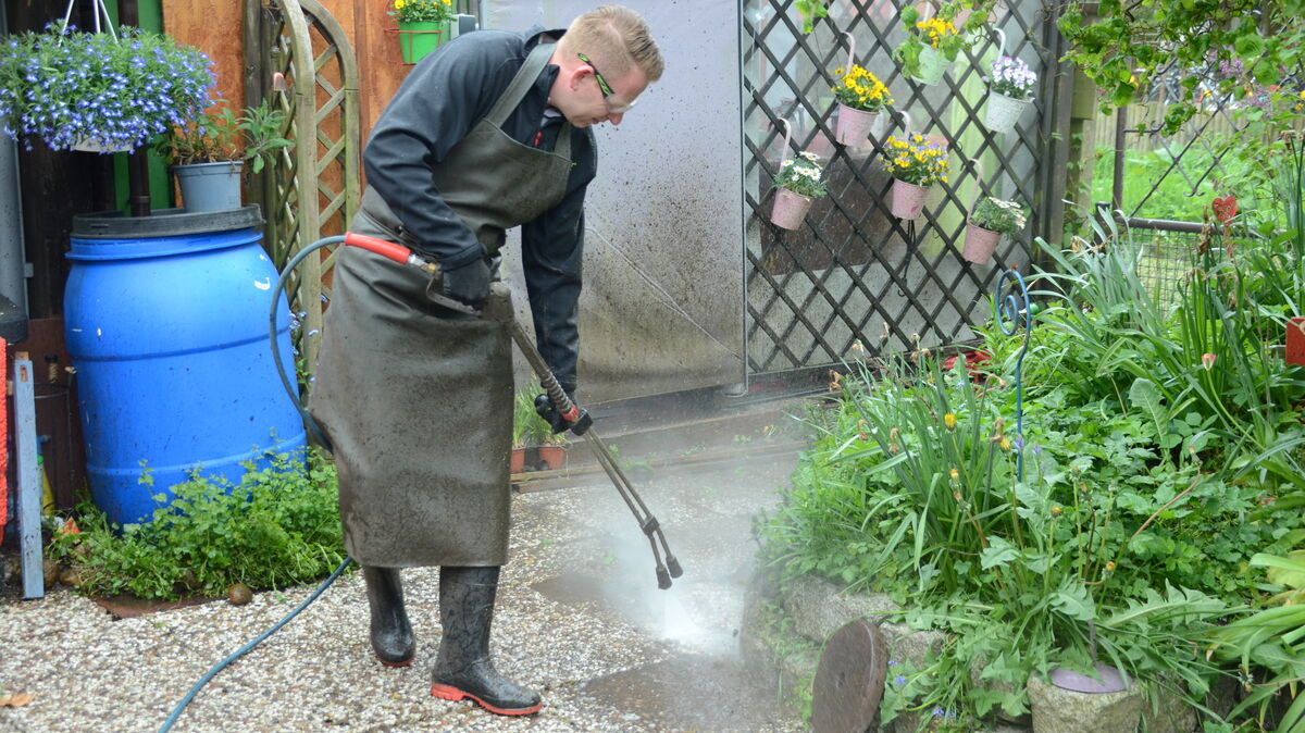 Ben Bachert von „SteinXpert Elbe-Weser“ auf der Terrasse von Familie Mickeleit bei Reinigen der Kanten mit der Hochdrucklanze. Foto: Rohde