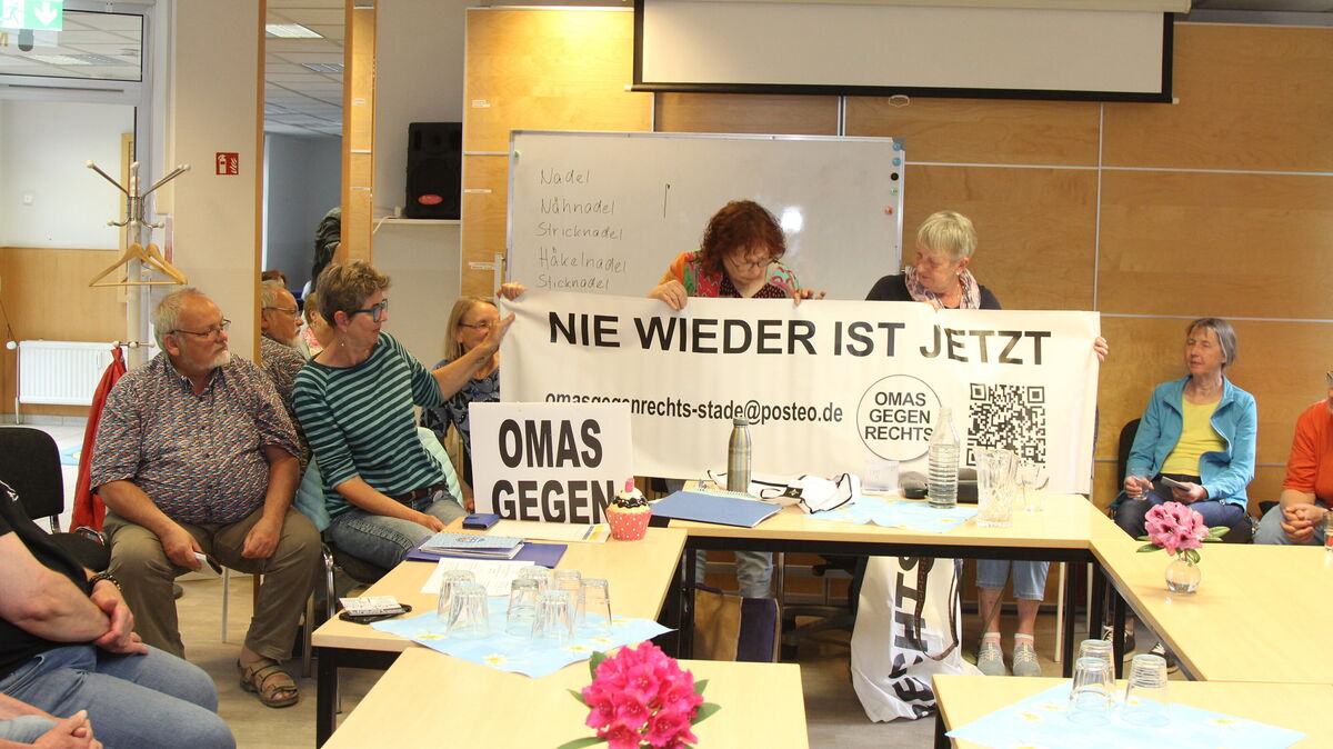 Schwarze Schrift auf weißem Grund - ein Erkennungszeichen der "Omas gegen Rechts". Das Transparent hatten Marion Meyer und Christiane Rosenthal-Leslie (stehend, v.l.) aus Stade mitgebracht, links von ihnen im Ringelshirt Karin Ottens-Spargel. Foto: Reese-Winne