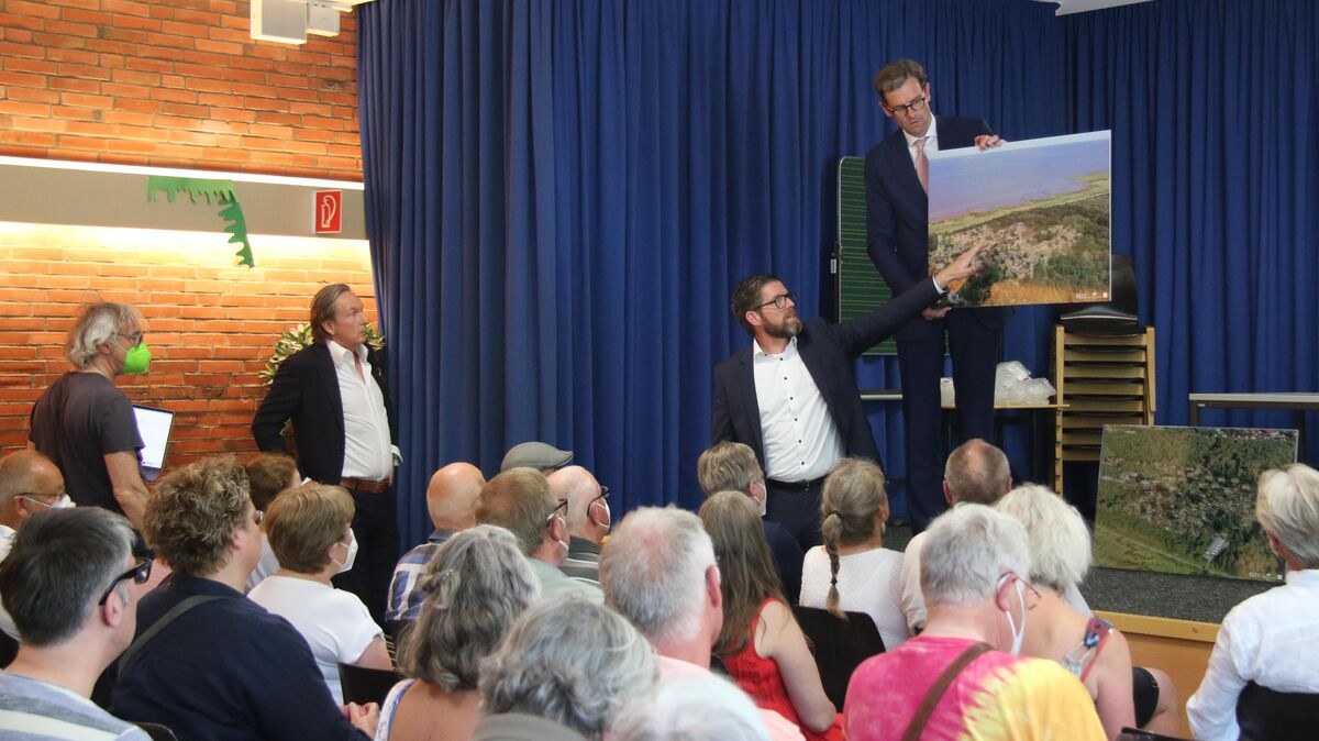 Erste bürgeröffentliche Präsentation: Florian Maas zeigt auf die Visualisierung des "Nordsee Natur Ressort", die Dr. Niels Bunzen in Händen hält. Links der dritte Partner des Investoren-Dreigestirns Claus-Dieter Stoldt. Foto: Potschka
