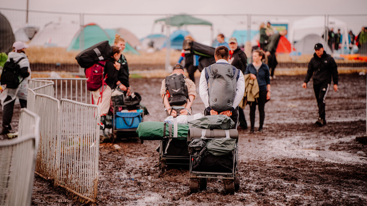 Festival-Besucher zogen ihr Gepäck 2023 durch den Matsch. Der Regen erschwerte die Abreise, die etliche Deichbrand-Gänger schon am Sonnabendabend antraten. Foto: Keck