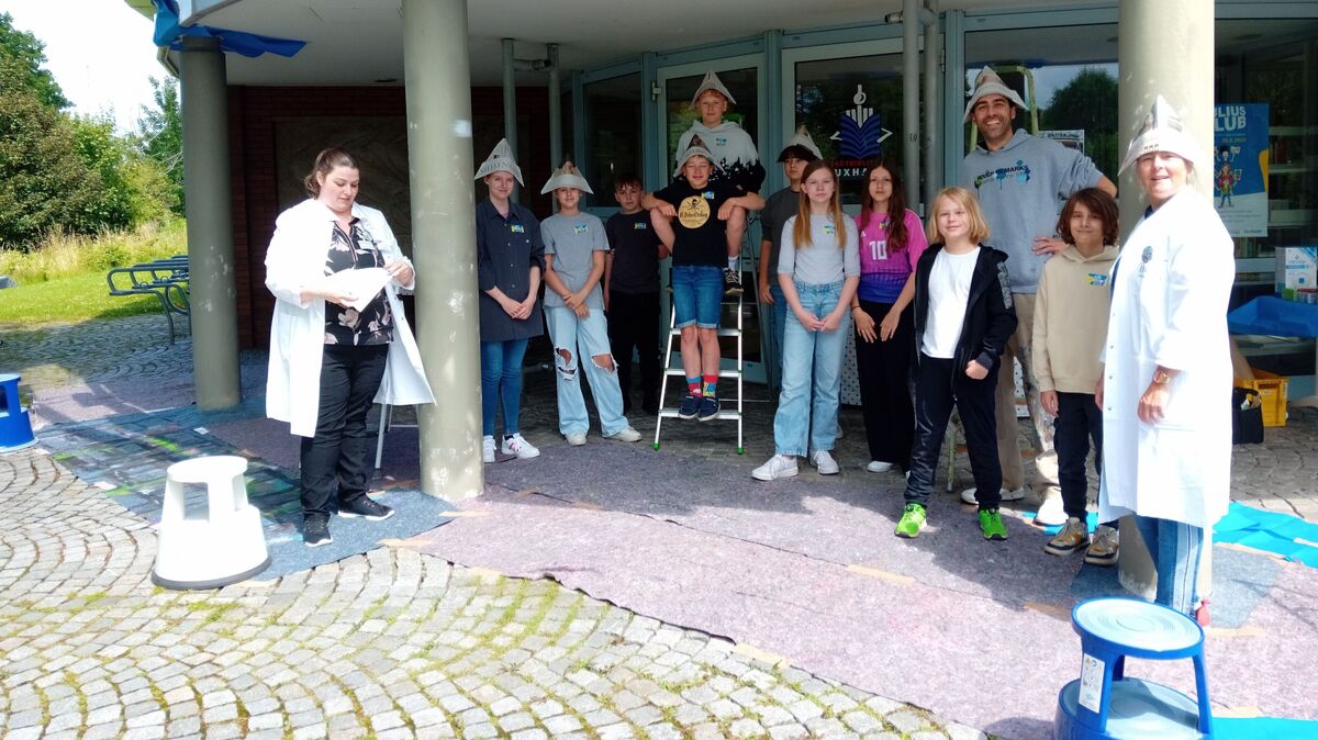 Die Teilnehmenden stehen voller Vorfreude mit Künstler Niels Hertel vor der Arbeit zu einem Gruppenfoto zusammen. Foto: Heiduschat