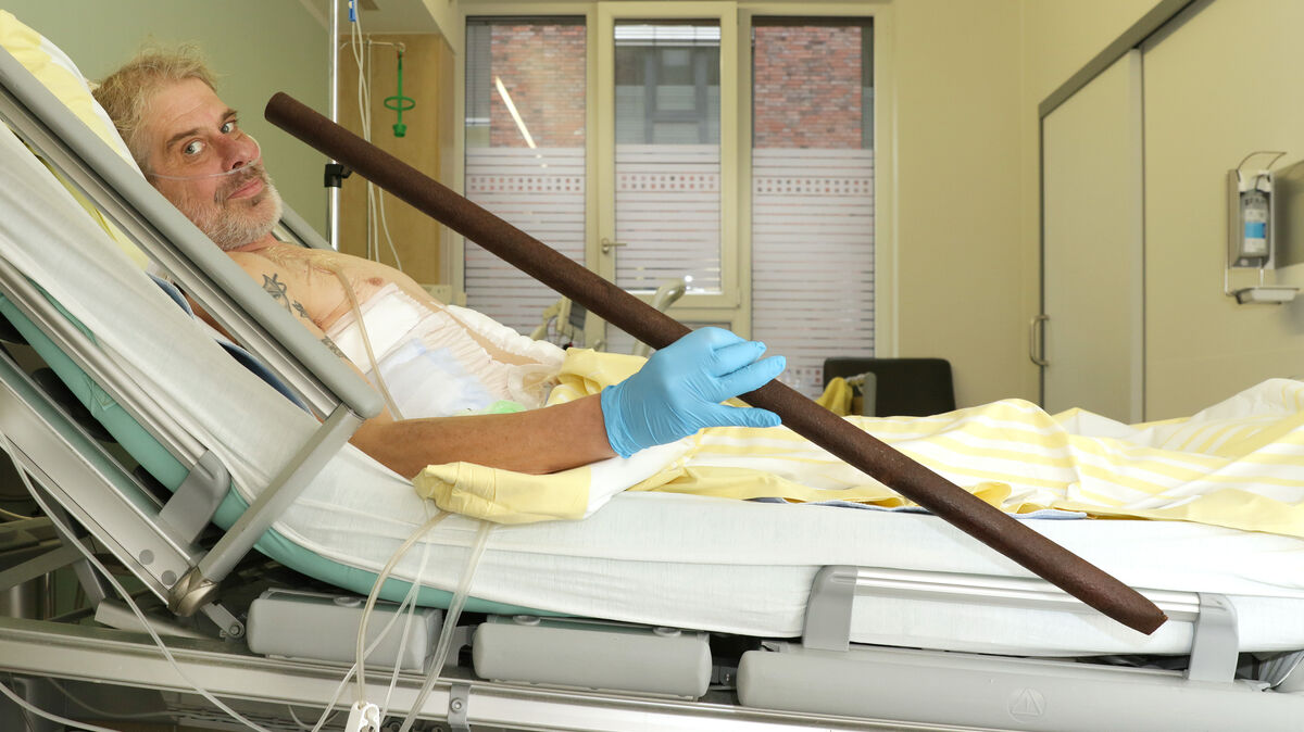Patient Frank Vaorin liegt im Krankenhausbett und hält die Zaunstange in der Hand, die seinen Körper durchbohrte. Foto: picture alliance/dpa/Gesundheit Nord – Klinikverbund Bremen | Kerstin Hase