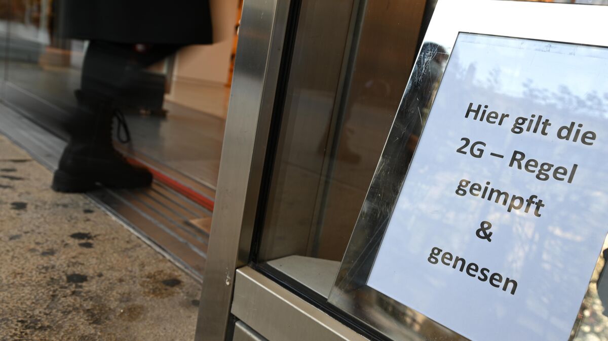 "Hier gilt die 2G-Regel": Hinweis hinter der Schaufensterscheibe eines Geschäftes. Foto Arne Dedert/dpa
