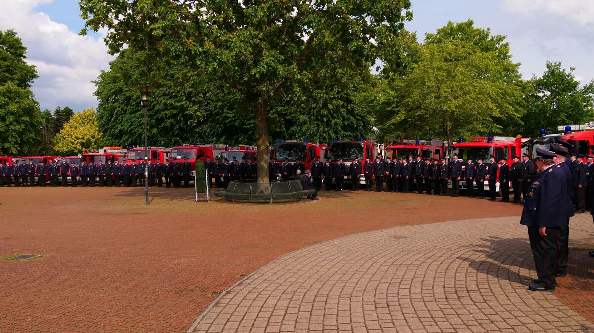 Vor der eindrucksvollen Kulisse aller neun Ortsfeuerwehren und deren Fahrzeugflotten kommen die Feuerwehrleute auf dem Schützenplatz zusammen. Foto: Lange